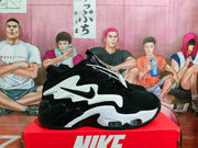 Side profile of a black and white Nike sneaker with layered panels and visible clear midsole sections.