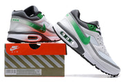 White and green Nike Air Max sneakers shown beside a branded shoe box; the box label shows a sample size.