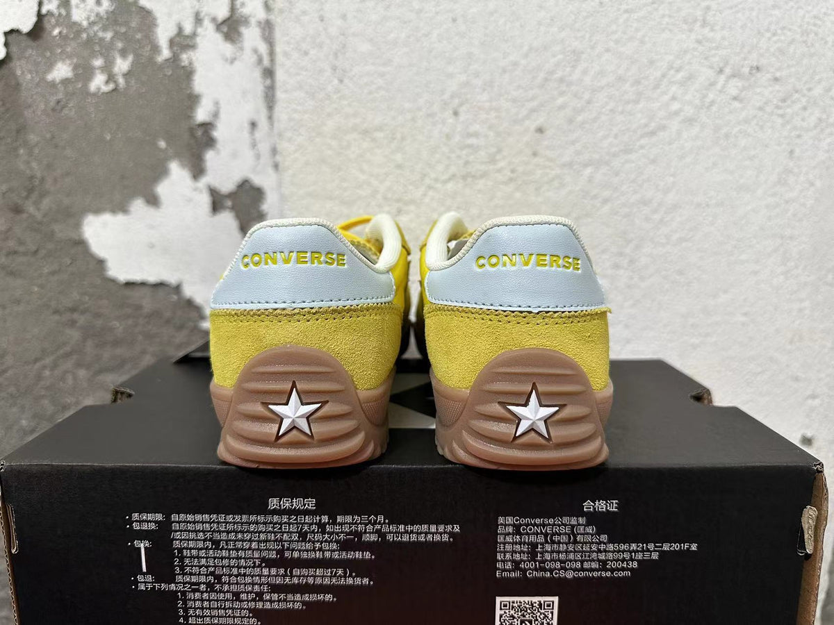 Rear view of yellow Converse training-style shoes with light-colored heel panels and gum-colored soles.