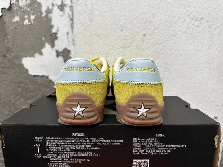 Rear view of yellow Converse training-style shoes with light-colored heel panels and gum-colored soles.