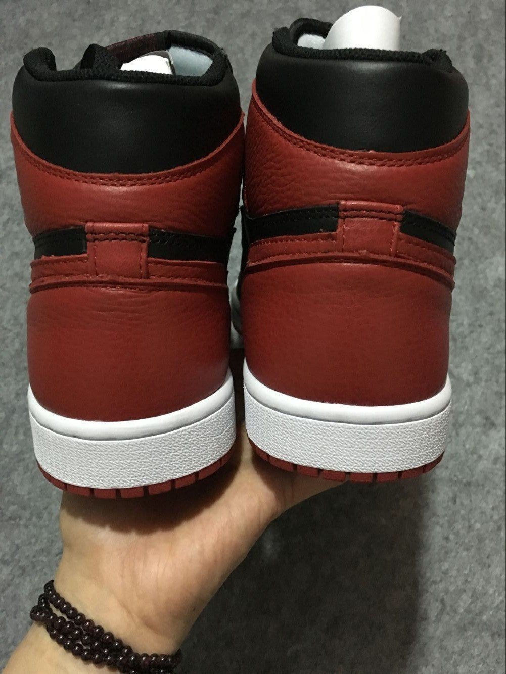 Rear view of black and red high-top sneakers with white midsoles and red outsoles.