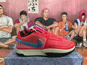 Side profile of a red Nike sneaker showing the mesh upper, blue side Swoosh-style accent, cream midsole, and black outsole.