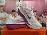 Pair of white Nike running shoes with pink accents and purple-toned soles, shown from the side