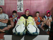 Front view of white Nike basketball shoes with yellow details, black swooshes, and blue-patterned soles.