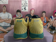 Rear view of yellow and green basketball sneakers with dark navy collars and 12-AM heel details, displayed on a shoebox.
