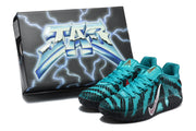 Teal and black sneakers displayed beside a black graphic shoe box.