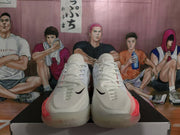 Front view of white Nike GT sneakers with peach-pink accents and black Swoosh logos.