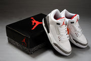 Pair of white and black Jordan sneakers displayed beside a black branded shoebox.