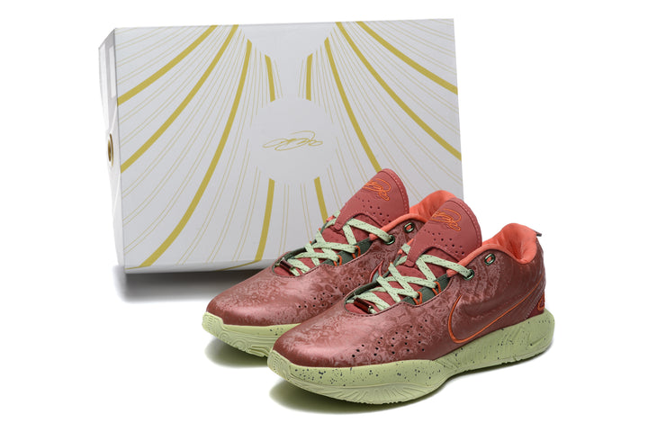 Pair of orange-red low-top sneakers with green soles and a matching patterned box.