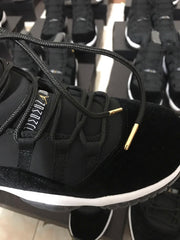 Close-up side view showing black laces with gold-colored aglets, textured black upper, and white midsole.