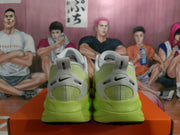 Rear view of green Nike sneakers showing black heel Swoosh details, white heel panels, and green soles.
