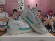 Angled view of paired grey Jordan basketball sneakers with teal accents, patterned side panels and lace-up construction.