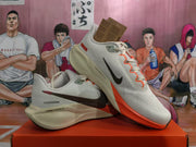 Angled view of the pair highlighting the black Swoosh, orange outsole, cream midsole, and lace-up construction.