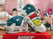 Angled view of Nike basketball shoes with oversized side graphics, teal panels, and a speckled sole.