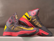 Pair of dark high-top basketball shoes with yellow and red accents