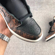 Close-up of the black perforated toe box, laces, and bronze-toned surrounding overlay.