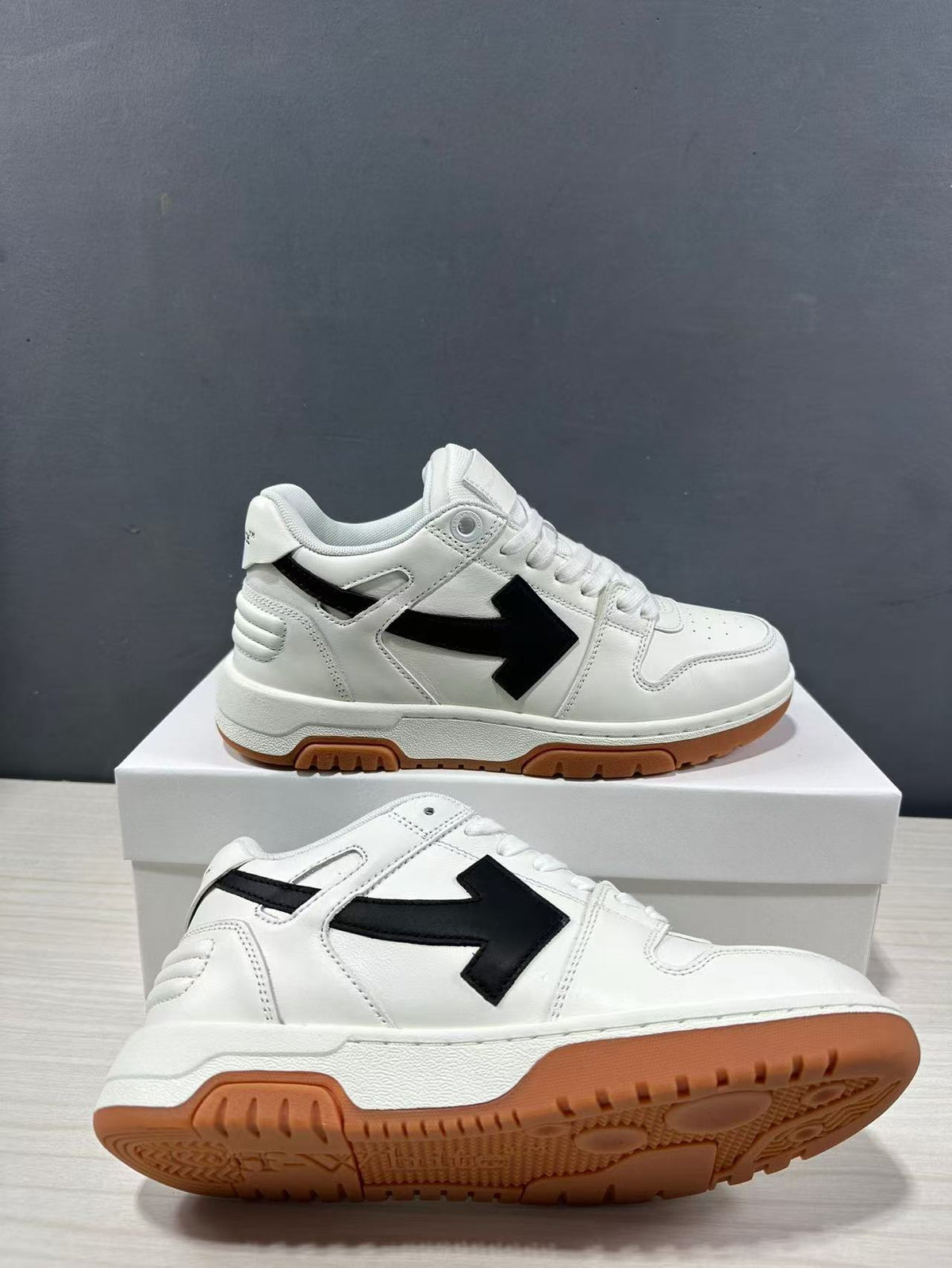 White Off-White Out Of Office sneakers with black side arrows, white laces, and gum-colored outsoles displayed on a box.