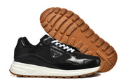 Two black low-top sneakers shown from the side, including a view of the gum-colored tread outsole.