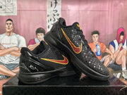 Angled view of two black Nike basketball sneakers displaying the textured uppers, contrasting Swoosh details, and thick black midsoles.