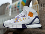 Side view of a white high-top Nike basketball shoe with purple map graphics, gold Swoosh, and orange side panel