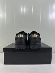 Rear view of the black sneaker pair showing gold-tone winged branding on the heels.