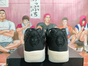 Rear view of black Nike sneakers showing tonal embroidered heel graphics and light-colored midsoles on a shoebox.