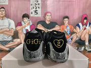 Rear view showing black heel panels with gold “GIGI” and heart-shaped “2” graphics.