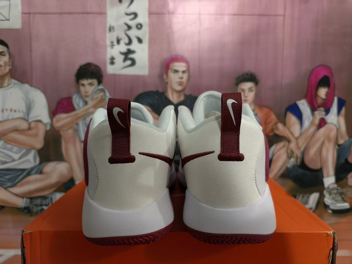 Rear view of white Nike basketball sneakers with burgundy-red heel pull tabs and outsole accents.