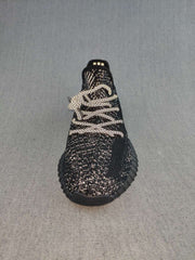 Front view of a black sneaker showing the rounded toe, light-colored laces, and textured speckled upper.