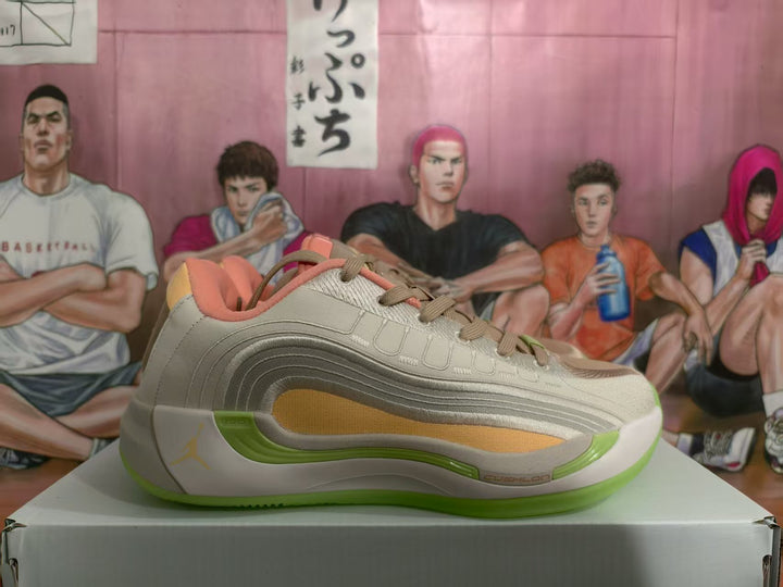 Side view of brown and light neutral Jordan sneakers with layered panels, coral collar padding, and translucent green outsole sections on a shoebox.