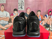Rear view of black basketball sneakers showing padded collars, glossy heel panels and translucent-looking outsoles on a red shoebox.