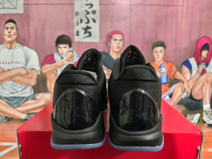 Rear view of black basketball sneakers showing padded collars, glossy heel panels and translucent-looking outsoles on a red shoebox.