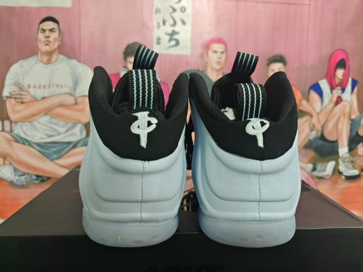 Rear view of white and black high-top basketball sneakers showing padded collars, striped pull tabs, and heel emblems.