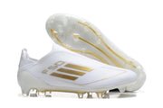 Side and outsole views of white adidas F50 soccer cleats with gold-colored accents and molded studs.