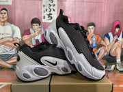 Angled view showing the patterned black uppers, side swooshes, white overlays, and oval sole details.