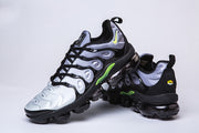 Nike TN-9 sneakers shown from the side and rear, highlighting green accents and segmented soles.