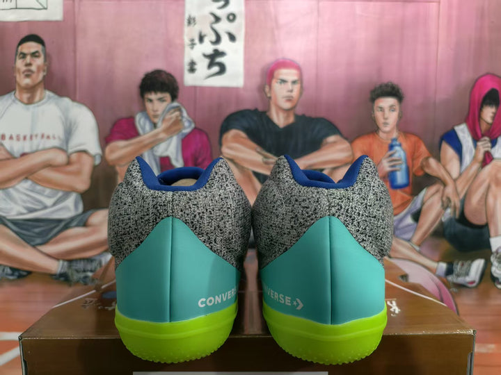 Rear view of grey Converse sneakers showing teal heel panels, blue collar lining, bright green outsoles, and visible Converse branding.