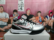 Side profile highlighting the silver-gray upper, black heel section, red Swoosh, and white-and-black outsole.
