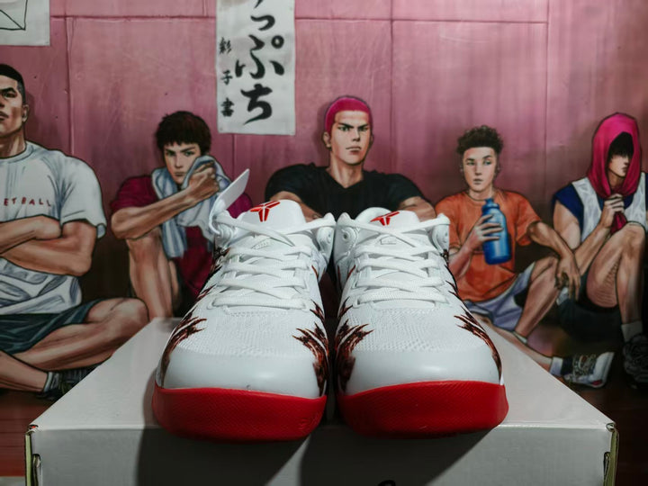 Front view of white Nike basketball sneakers with red toe outsoles and dark graphic details on the uppers.