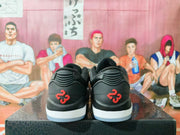 Rear view of black low-top sneakers showing red number 23 heel details, white midsoles, and a basketball-themed background.