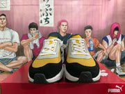 Front view of yellow, black and gray PUMA sneakers with white laces