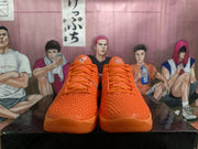 Front view of bright orange Nike basketball sneakers with textured uppers, orange laces, and metallic silver Swoosh details.