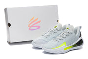 Pair of light grey basketball shoes beside a box, with white soles and bright volt accents.