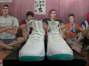 Front view of white lace-up high-top basketball shoes with teal outsoles