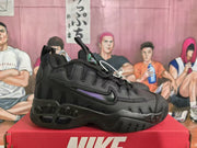 Side view of a black Nike sneaker with a purple side accent, layered upper panels, and a sculpted outsole.