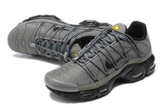 Angled top view of a grey Nike Air Max Plus sneaker with grey laces and black Swoosh.