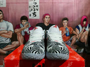 Front view of zebra-print Nike basketball sneakers with white laces, padded tongues, red tongue branding, and translucent outsoles.