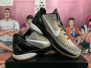 Angled display of black and beige Nike basketball sneakers showing the textured upper, white Swoosh, patterned laces, glossy heel, and gum-colored outsole.