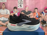 Side view of a black Brooks shoe with gray detailing, red branding, and a white midsole.