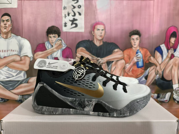 Side view of carbon gray Nike basketball sneakers with a gold swoosh, black overlays, and a marbled gray outsole.